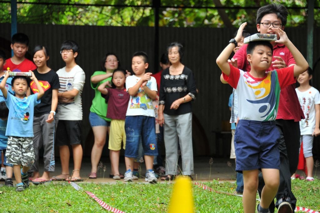 Kids playing outdoor balancing game on grass, to celebrate school birthdays without food