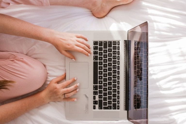 Woman using laptop on bed, allergy YouTube channels
